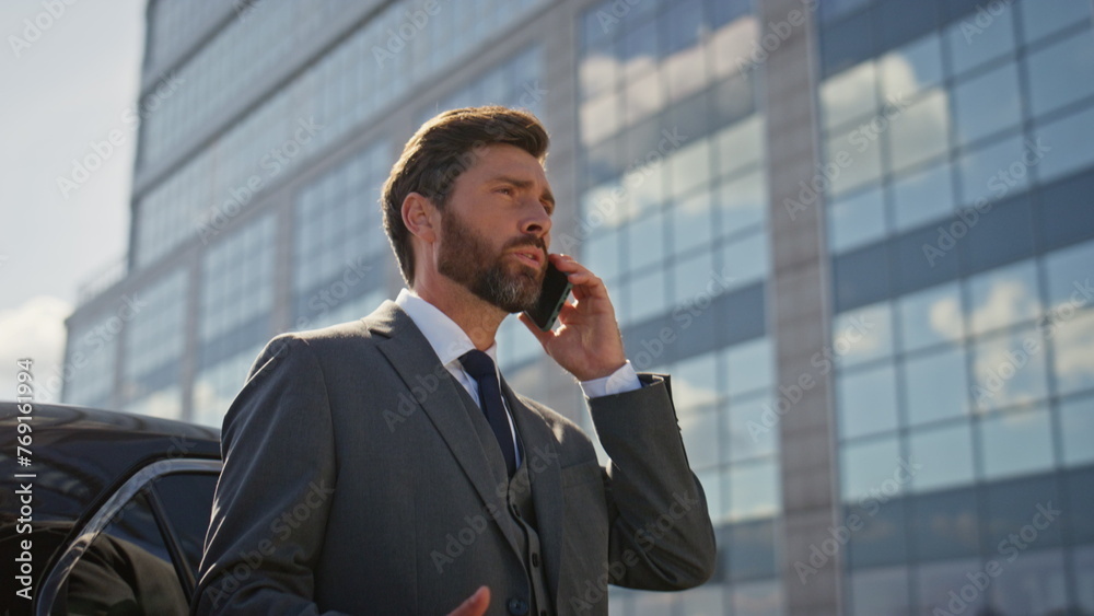 Worried ceo speaking smartphone near luxury car at sunny street close up. Worried ceo speaking smartphone near luxury car at sunny street close up.