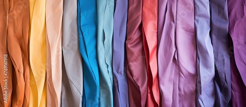 A close up of a variety of colorful fabrics displayed by hanging them on a wall in a neat arrangement