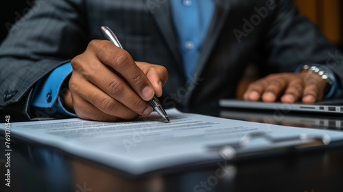 a person in a grey suit and blue shirt, seated at a dark-colored desk. He is writing on a piece of paper,generative ai
