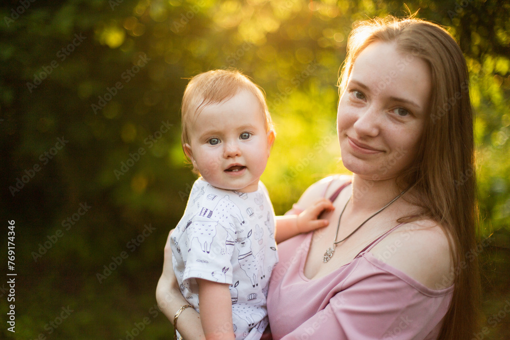 Mother holds his little daughter in his arms, summer sunset