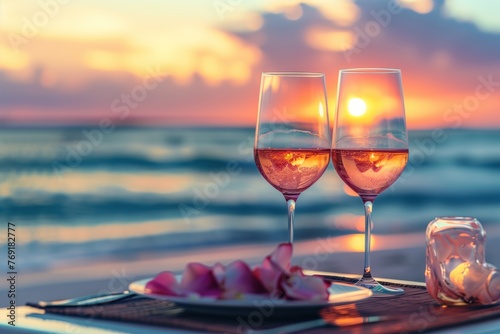 Two glasses of drinks with rose petals on a table at sea beach during sunset