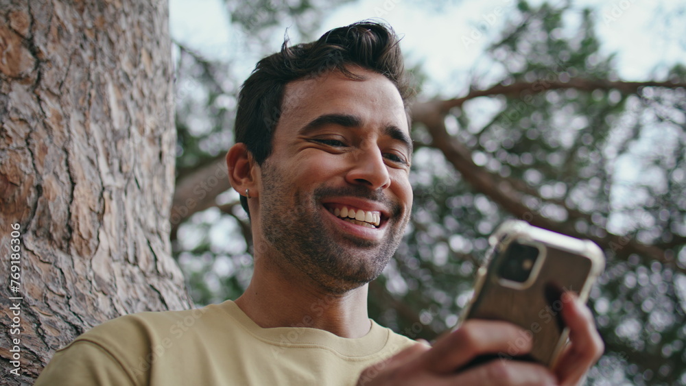 Laughing hipster watching smartphone social networks at park weekend close up