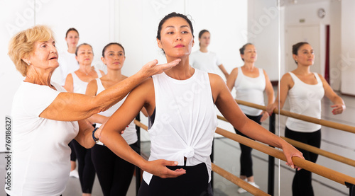 Dancing Asian woman doing ballet in a female group in the studio is standing in a ballet stance  where the choreographer ..helps to perform the exercise correctly