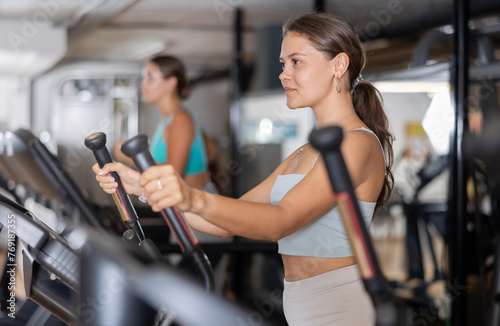 Young sporty girl working out on elliptical machine in gym. Healthy active lifestyle concept