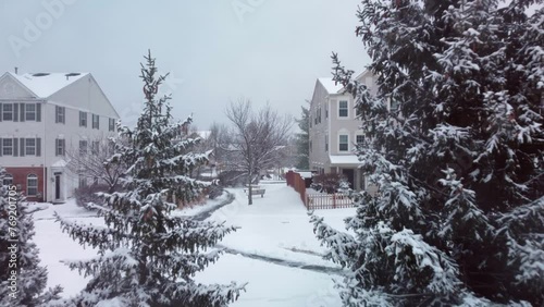 Drone glides through snow covered pine trees.