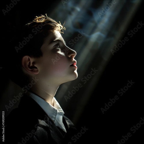 Young jewish boy Kippah, being bar mitzvah in dark room with shafts of light: coming-of-age religion, boy to man