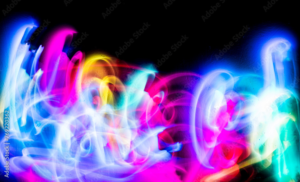 Abstract colorful irregular lines on black background and wall texture. Long exposure. Light painting photography.
