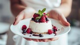 Close-up of delicate female hands cradling a white plate adorned with a delectable fresh berry dessert, Ai Generated