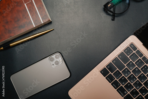 Business layout with items for design. Phone, glasses, pen, laptop on the table. In a dark style, there are object layouts on the table. Top view of items
