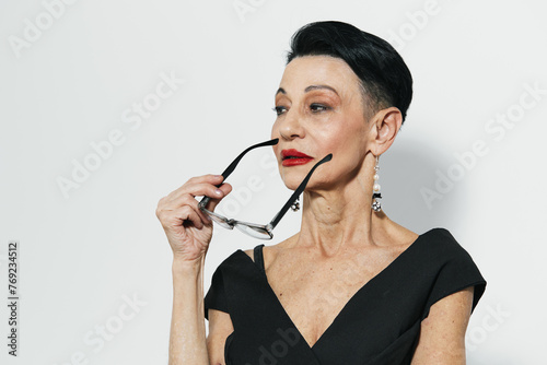Beautiful woman in black dress holding fashionable eyeglasses up to her face, elegant and sophisticated look concept