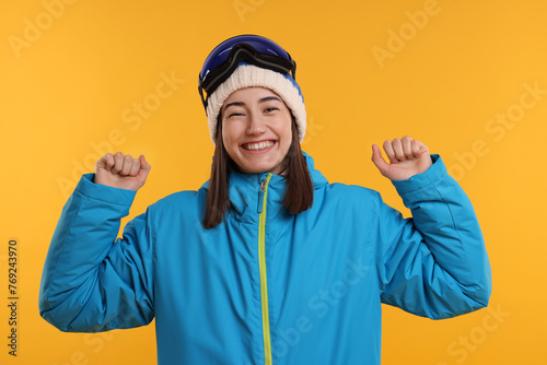 Winter sports. Excited woman with snowboard goggles on orange background
