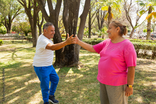 A woman and an adult man greet each other warmly as they arrive at their aerobics class.