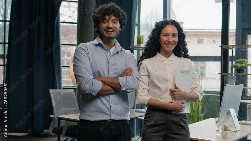 Obraz premium Two multiracial business team professional partners diverse colleagues with crossed hands employees co-workers Indian businessman and Arabian businesswoman smiling confident pose in corporate office
