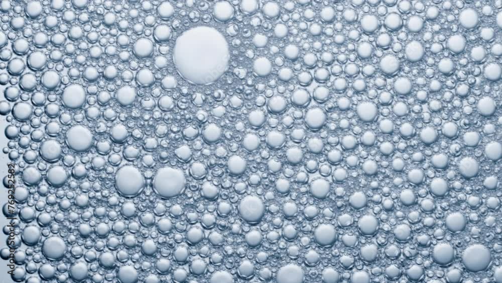 Multitude of air bubbles in a soap solution, bubbles burst on contact with air.