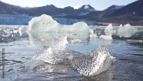 Pieces of Broken Ice Under Glacier, Melting in Water on Sunny Day photo