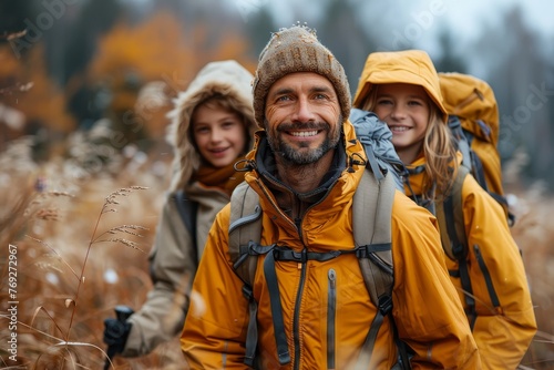 A father with two children smiling warmly while hiking in an autumn field with mist