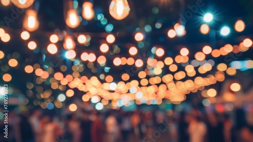 A crowded festival street illuminated at night, showing a blurry group of people standing around.