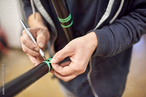 Unknown man preparing a bicycle frame with a scalpel and masking tape for a custom painting design in his bike workshop.