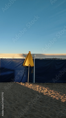 Obraz na płótnie Yellow umbrella closed over beach tents during the golden hour in Pinamar, Buenos Aires, Argentina. w salonie