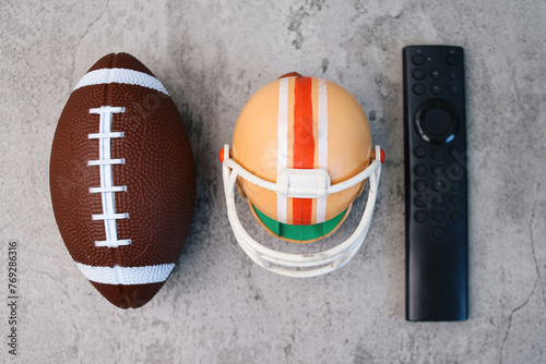 Rugby ball, helmet and remote control in watching super bowl games on television concept photo