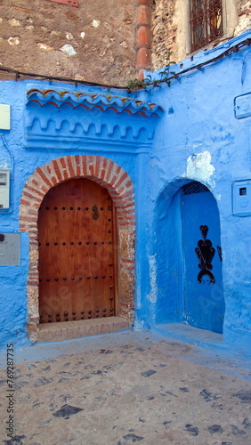 Wooden door in a blue wall in the medina in Chefchaouen, Morocco © Angela