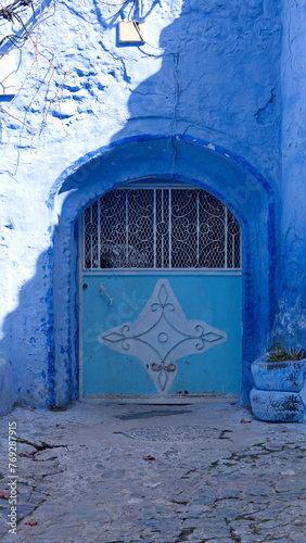 Small, blue, metal door in a blue wall in the medina in Chefchaouen, Morocco © Angela
