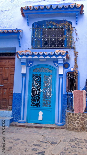 Blue, metal door with a grate in a blue wall in the medina in Chefchaouen, Morocco © Angela