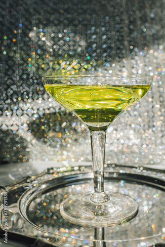 chartreuse green cocktail in coupe glass with sparkling silver background	