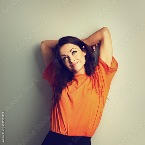 Beautiful young relaxing woman in casual clothing thinking and looking up in orange casual shirt on blue studio background on empty copy space. Closeup