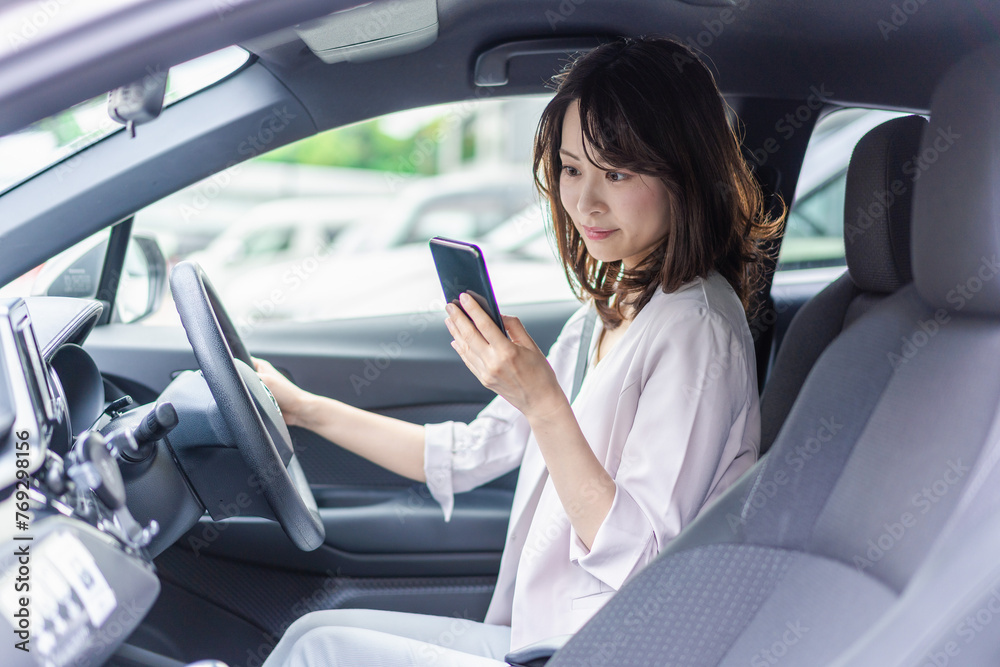 スマホを使いながら車を運転する女性