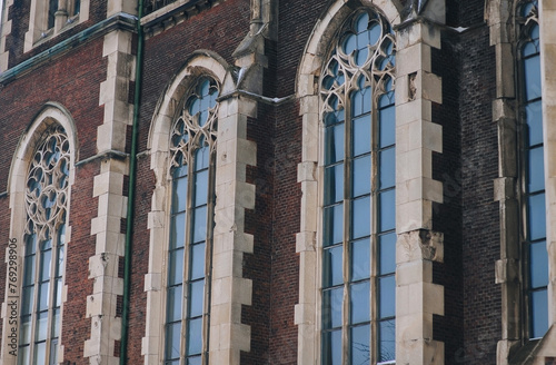Three old pointed openwork gothic windows with stained glass on facade of the building. Baroque and Gothic architecture. Church of St. Olga and Elizabeth. Lviv, Ukraine.