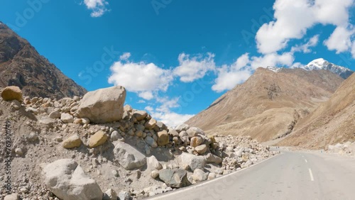 4K POV shot of a vehicle moving on an asphalt road in the middle of the Himalayas during sunny day against blue sky with clouds on the way to Shinkula Pass from Darcha in Himachal Pradesh, India. photo