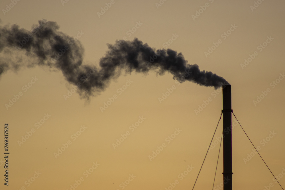 Smoke from the chimney of an industrial plant at sunset.