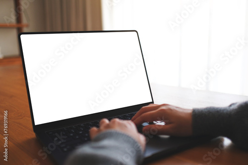 Mockup image of a woman working and typing on laptop computer with blank white desktop screen at home