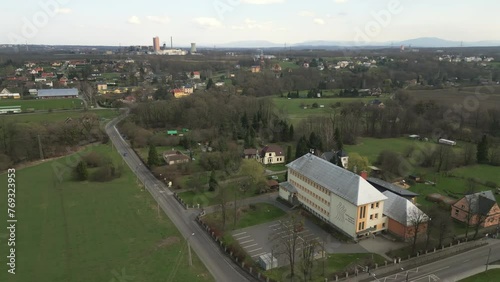 Aerial view of Stonava village, showcasing a mix of green landscapes, residential buildings,school and roads under a cloudy sky. photo