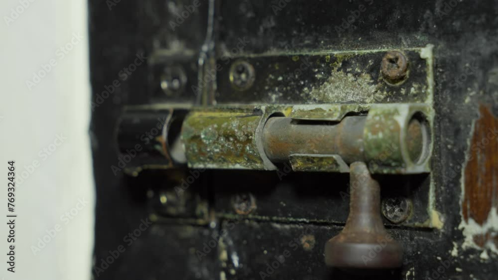 Hand turning a rusty old door lock with visible wear and tear, close-up Hand turning a rusty old door lock with visible wear and tear, close-up