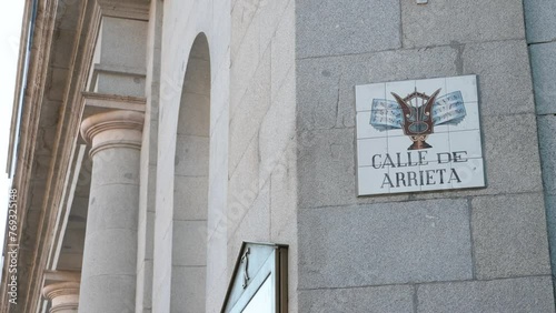 A street name sign announcing  the location of Arrieta street (calle de Arrieta) hangs from the Teatro Real (Royal Theatre) building at the Isabel II plaza in Spain. photo