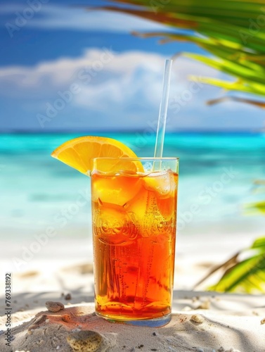 A glass of tea with an orange slice in it is sitting on a beach