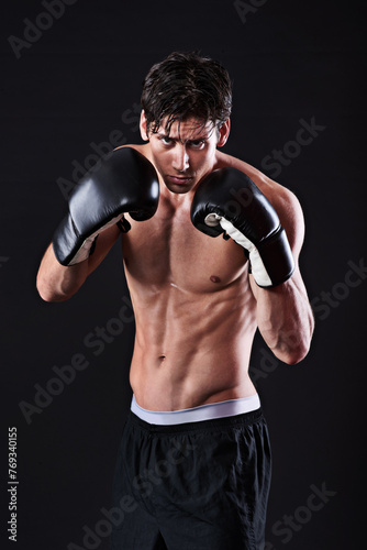 Man, portrait and boxing gloves in studio for exercise fight or martial arts training or performance, black background or gym. Male person, face and self defence fitness for athlete, mockup or punch © peopleimages.com