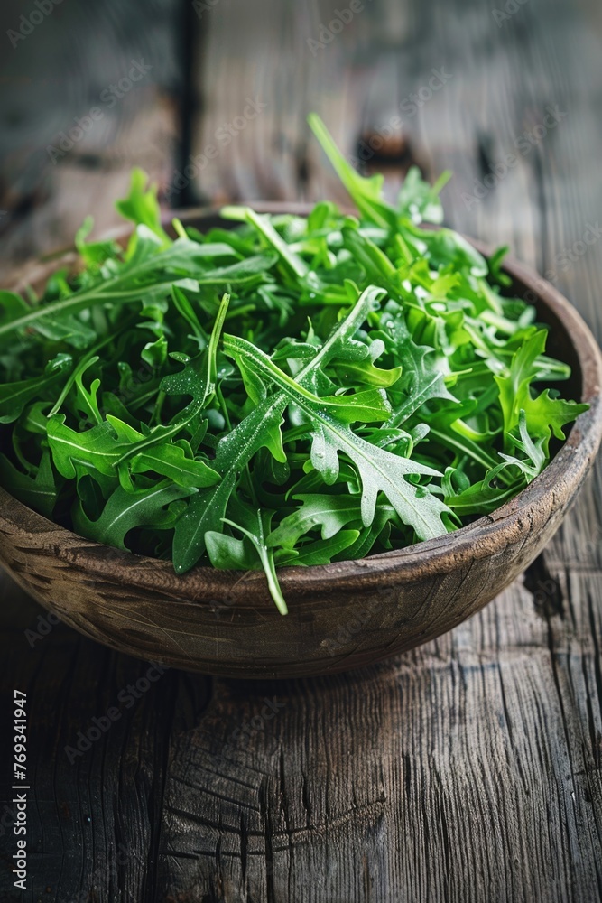 A bowl of green leafy vegetables sits on a wooden table A bowl of green leafy vegetables sits on a wooden table