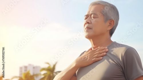 close up mid-age man with sweat and using hand touch chest with feeling tried and unable to breath against hot sunny sky background photo