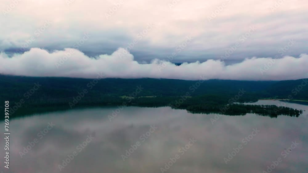 Mountain Lake with Dark Clouds Rolling Over Hills of a Peaceful Clear Body of Water with Reflection of Sky on the Water. Aerial Drone View Mountain Lake with Dark Clouds Rolling Over Hills of a Peaceful Clear Body of Water with Reflection of Sky on the Water. Aerial Drone View