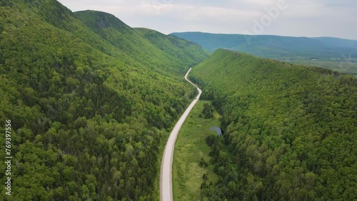 Drone shot of a stunning scenery of the famous Cabot Trail with a huge mountain range with a road going straight through the middle located on Cape Breton Island, Nova Scotia in Canada shot in 4k. photo