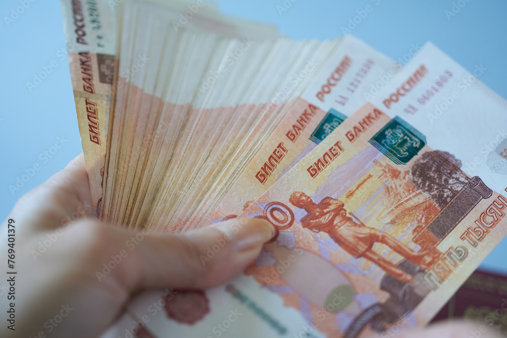 Hand holding a bundle of banknotes of five thousand rubles. 5000 rubles. - obrazy, fototapety, plakaty 