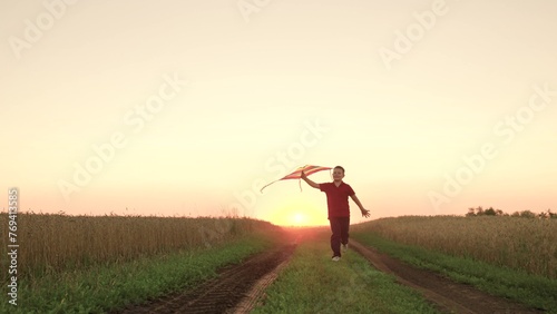 child kid baby boy runs across field with rainbow kite hands sunset  children s dream flying  airplane pilot  happy boy playing with flying kite park sunset  feeling freedom vacation  flying kite
