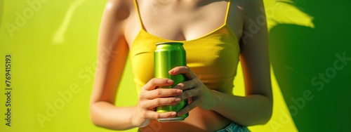 Close-up of a young woman in a yellow tank top holding a green can of beer