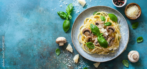 Pasta mushrooms with parmesan and basil on light blue background, copy space.