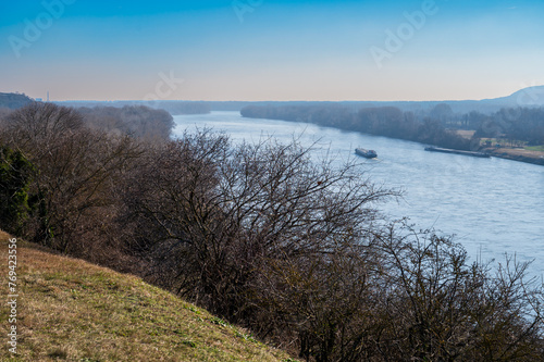 View from the hill on the Danube river in Bratislava. There is a cargo ship on the river. Autumn. Blue sky.