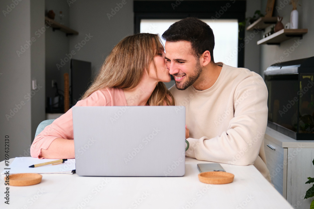 Woman kissing her boyfriend while using the laptop. Woman kissing her boyfriend while using the laptop.