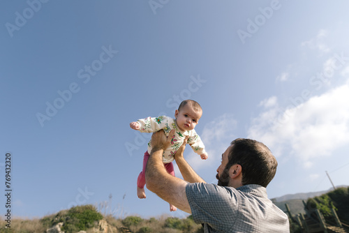 Baby Reacts Mildly To Being Held Up High By Father While Outside